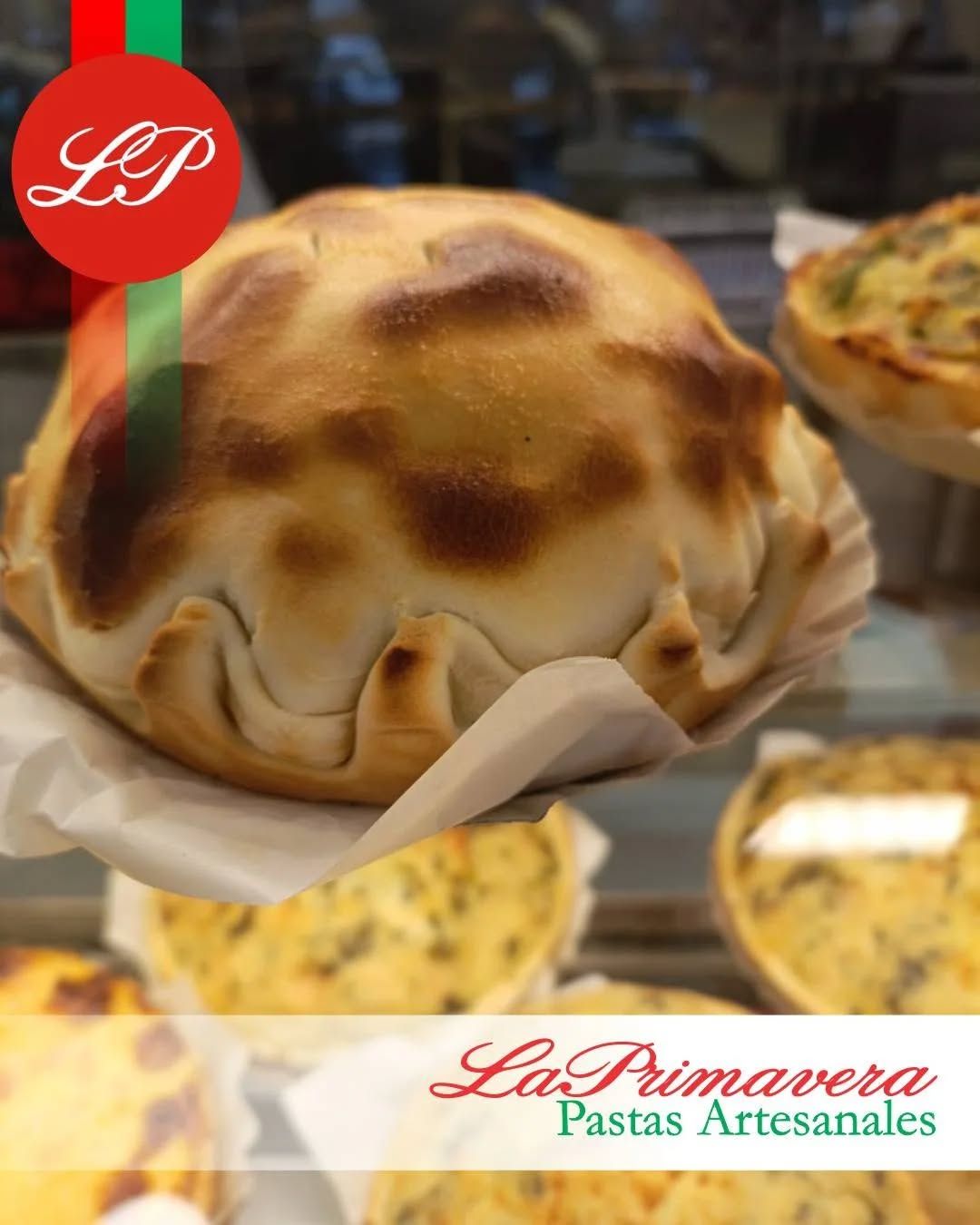 Una empanada horneada de color dorado sobre papel blanco, con el logo de