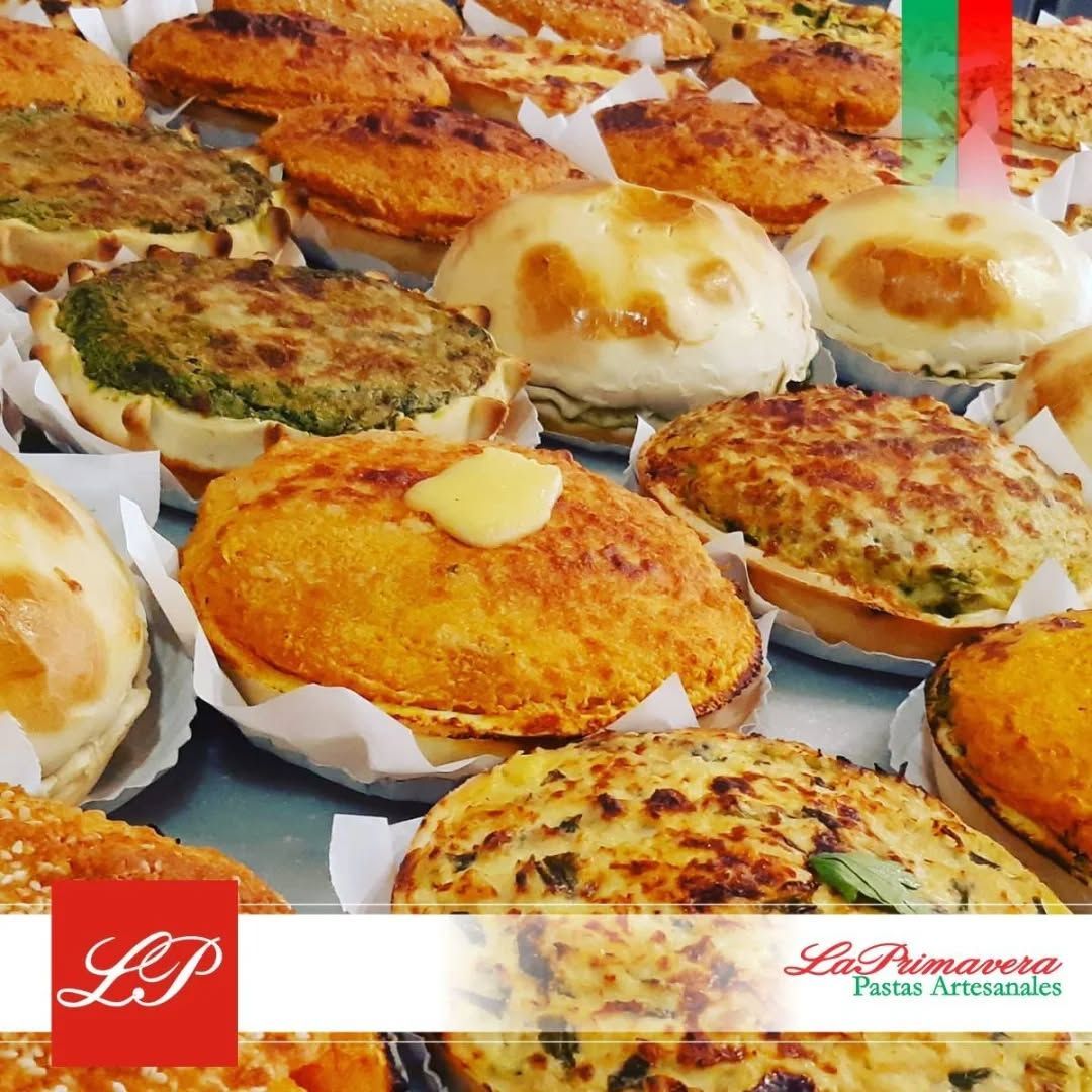 Surtido de pasteles horneados dorados en exposición, posiblemente en una panadería.