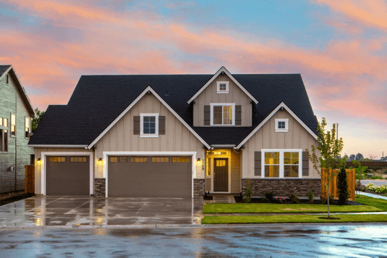 exterior home painted beige shown at dusk with lights on