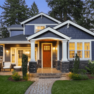 exterior home painted navy shown at dusk with lights on