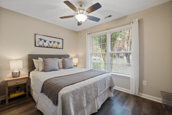 beautifully painted and staged interior bedroom with large window and ceiling fan