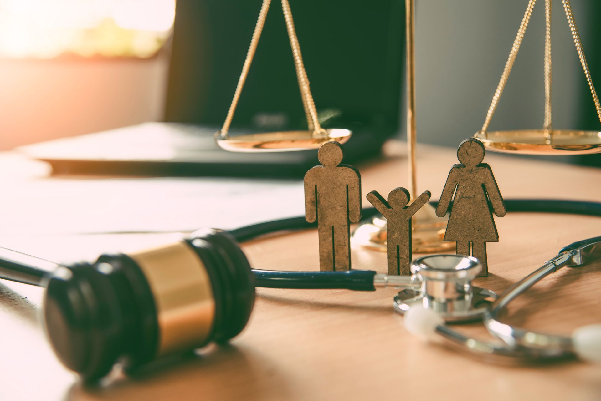 A wooden family, scales of justice, stethoscope, and gavel on a wooden table.