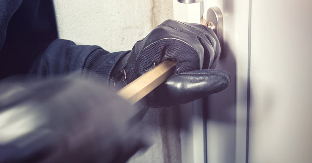A burglar is breaking into a door with a hammer.