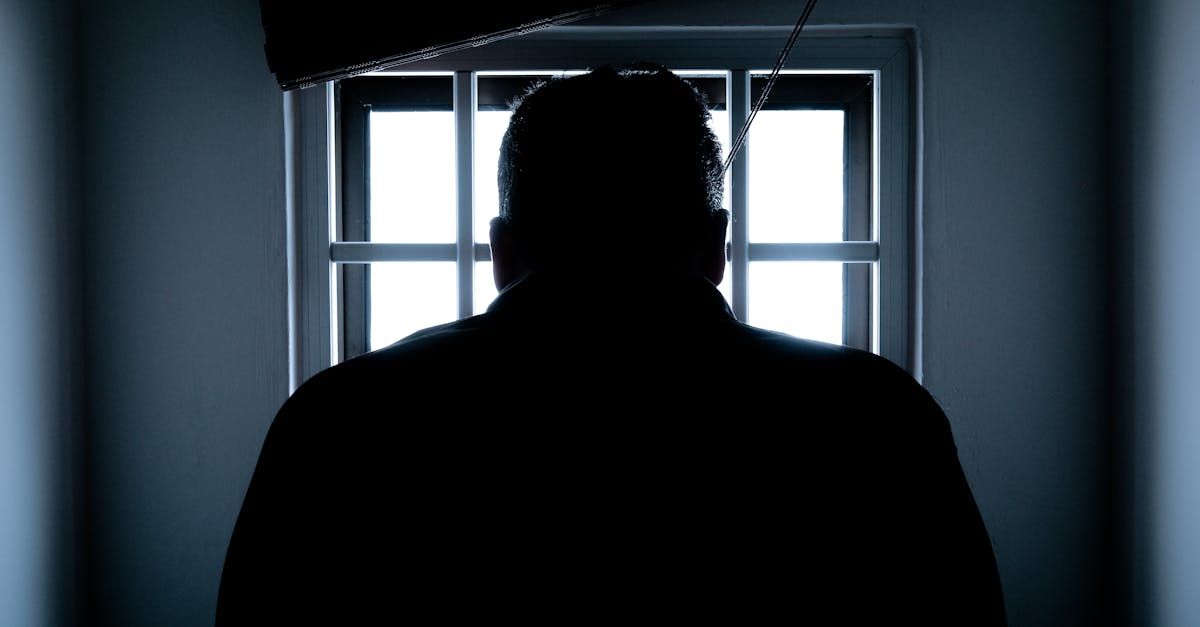 A man is standing in front of a window in a dark room.
