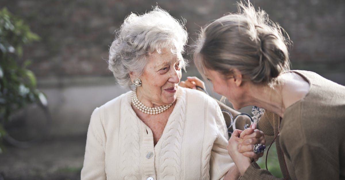 A woman is feeding an older woman with a spoon.
