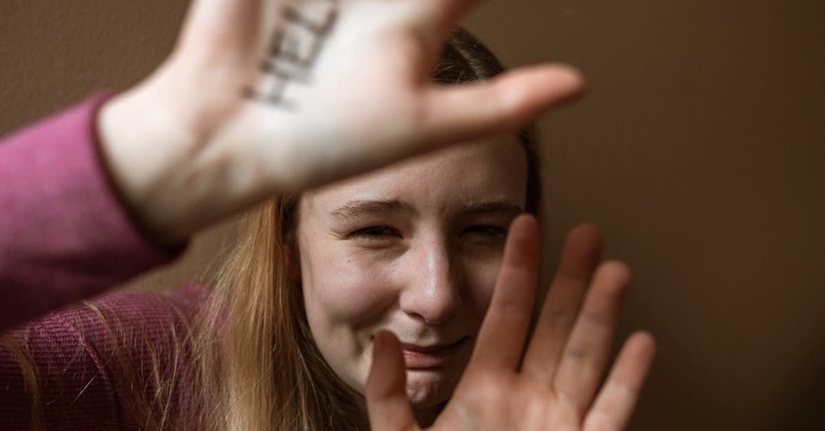 A woman with a tattoo on her hand is covering her face with her hands.