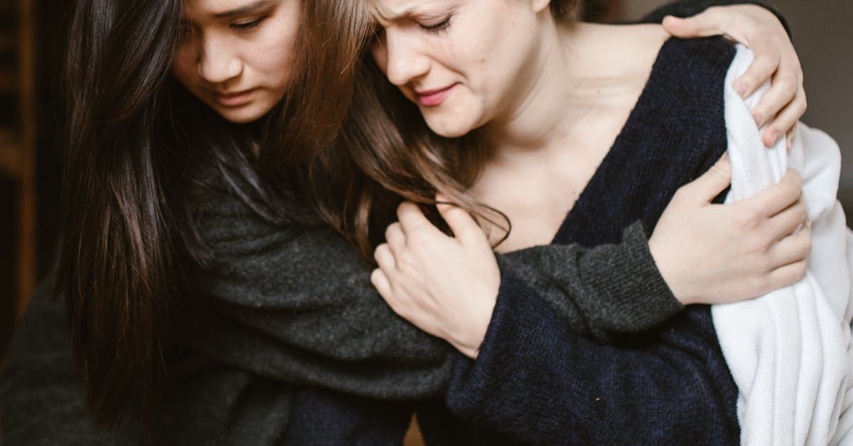 Two women are hugging each other while sitting next to each other.