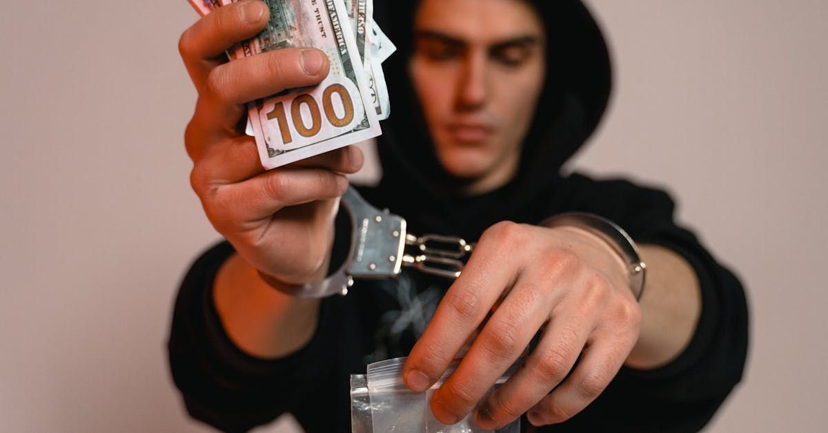 A man in handcuffs is holding a stack of money.