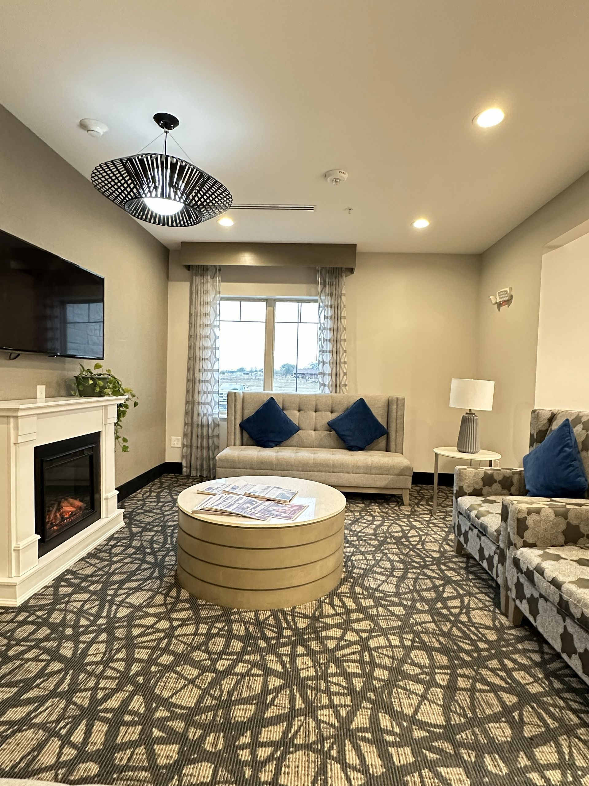 Cozy living room with fireplace, sofas, round coffee table, and patterned carpet.