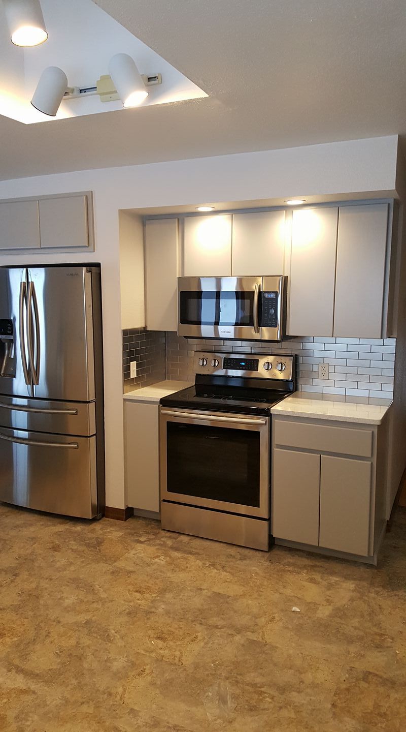 Modern kitchen with stainless steel fridge, stove, microwave, and white cabinets under ceiling lights