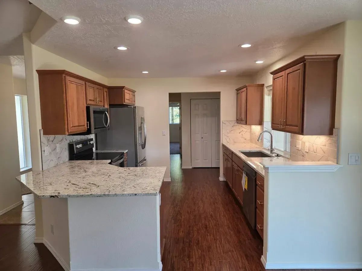 Bright kitchen with wood cabinets, granite countertops, stainless appliances, and recessed lighting