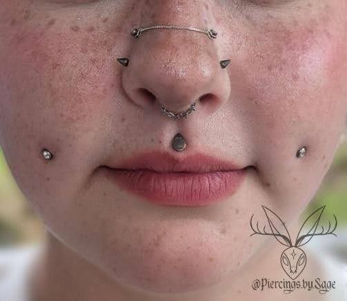 A close up of a woman 's face with multiple piercings.
