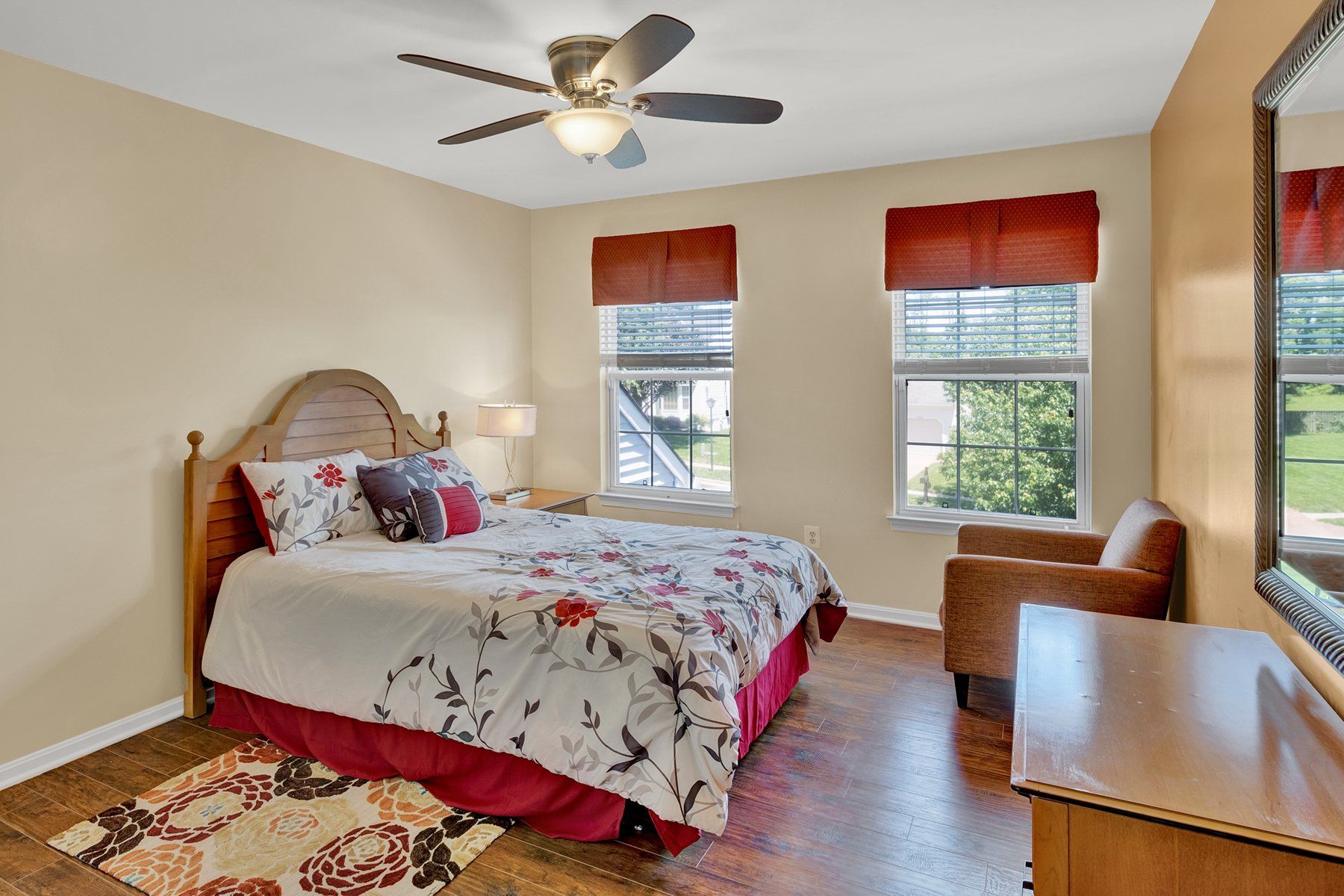 A bedroom with a bed , chair , dresser and ceiling fan.