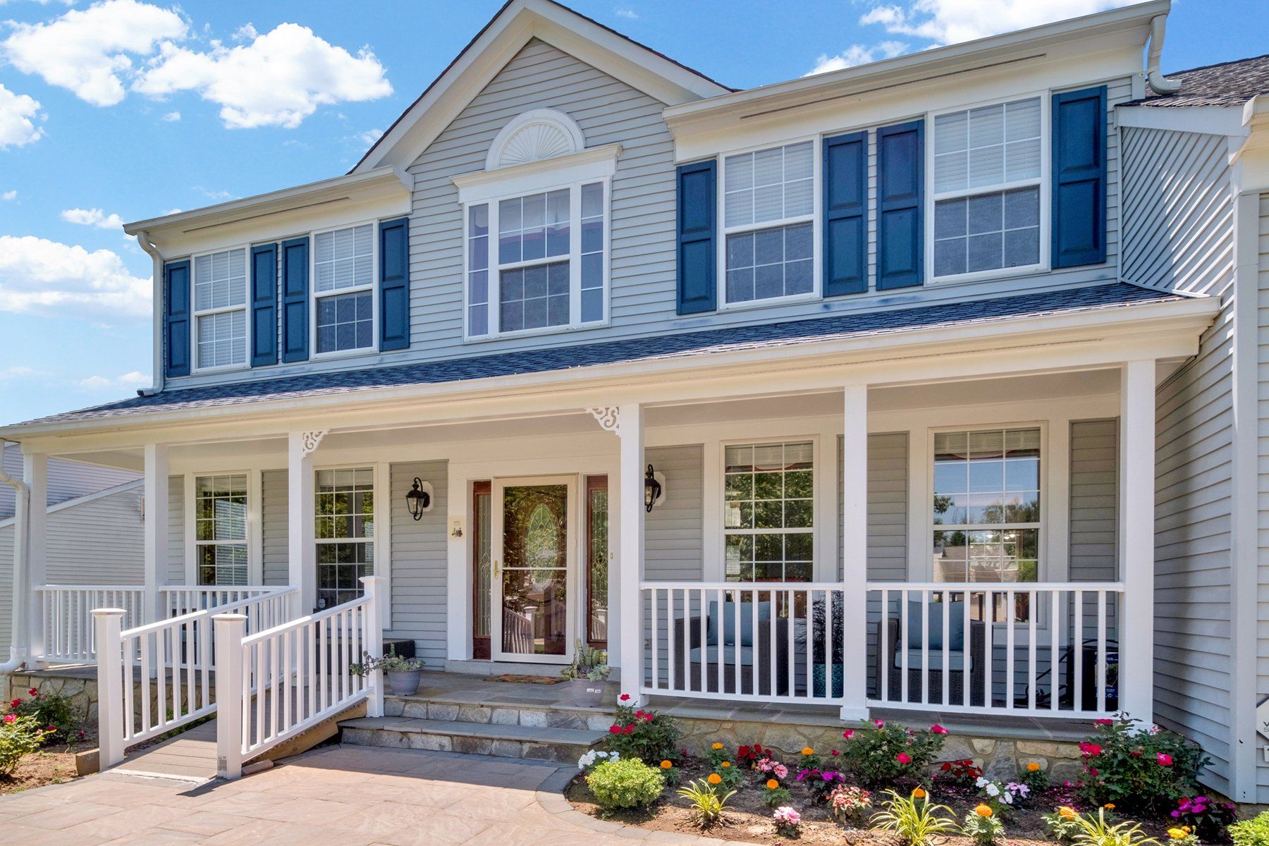 A large white house with blue shutters and a large porch.
