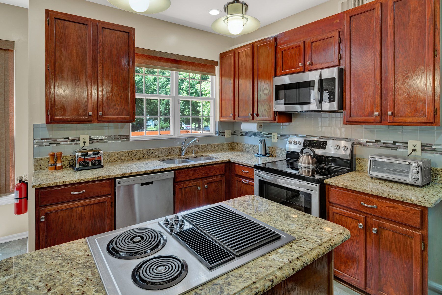 A kitchen with wooden cabinets , granite counter tops , stainless steel appliances and a stove top oven.