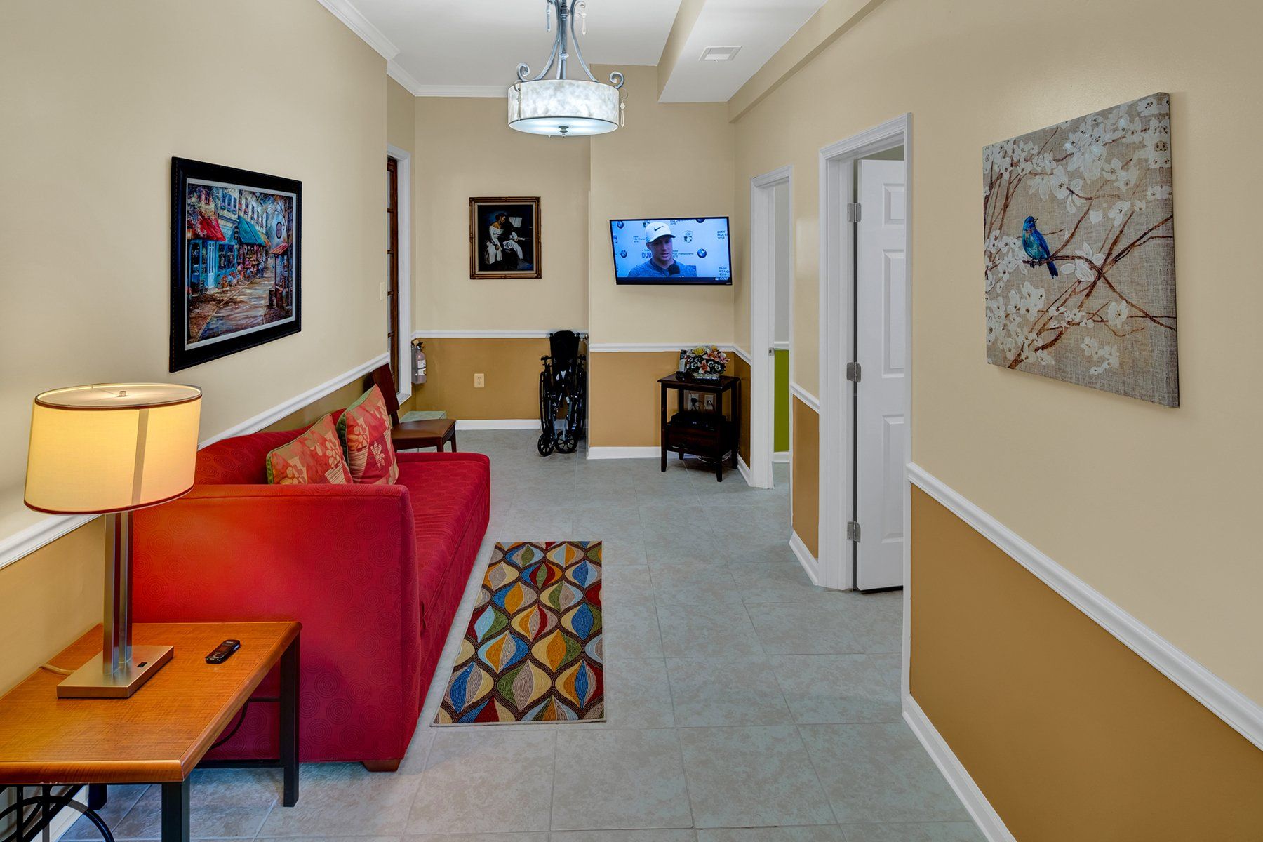 A living room with a red couch , table , lamp and television.
