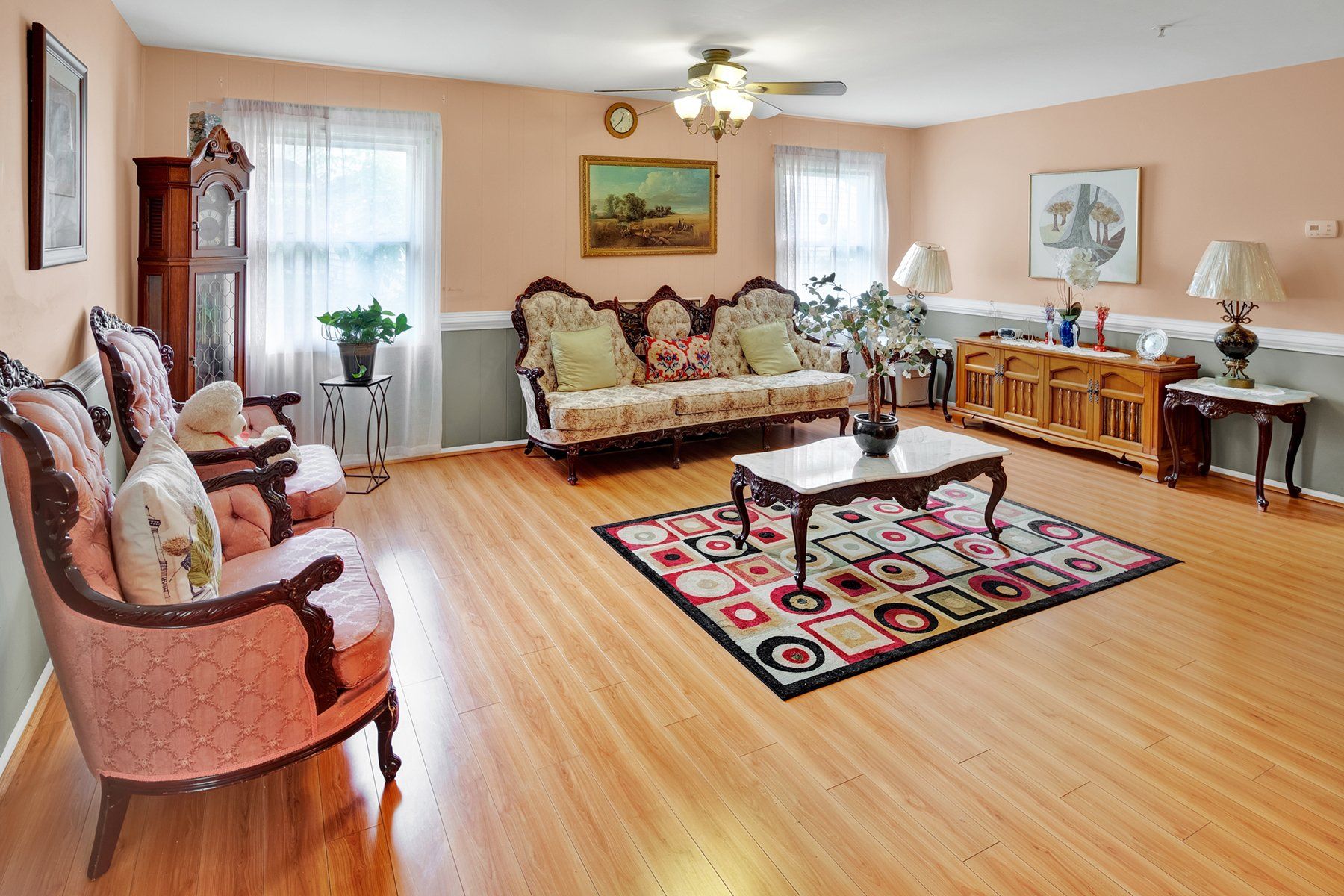 A living room with a couch , chairs , a coffee table and a rug.