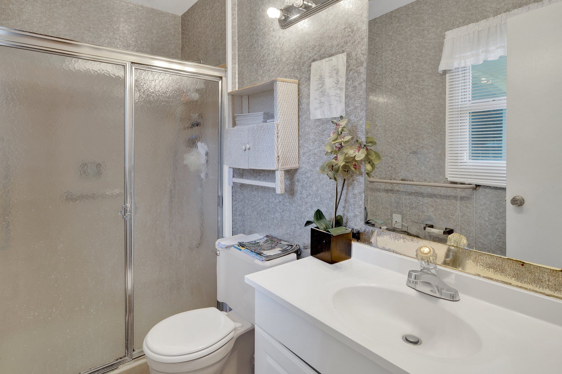 A bathroom with a toilet , sink , and shower.