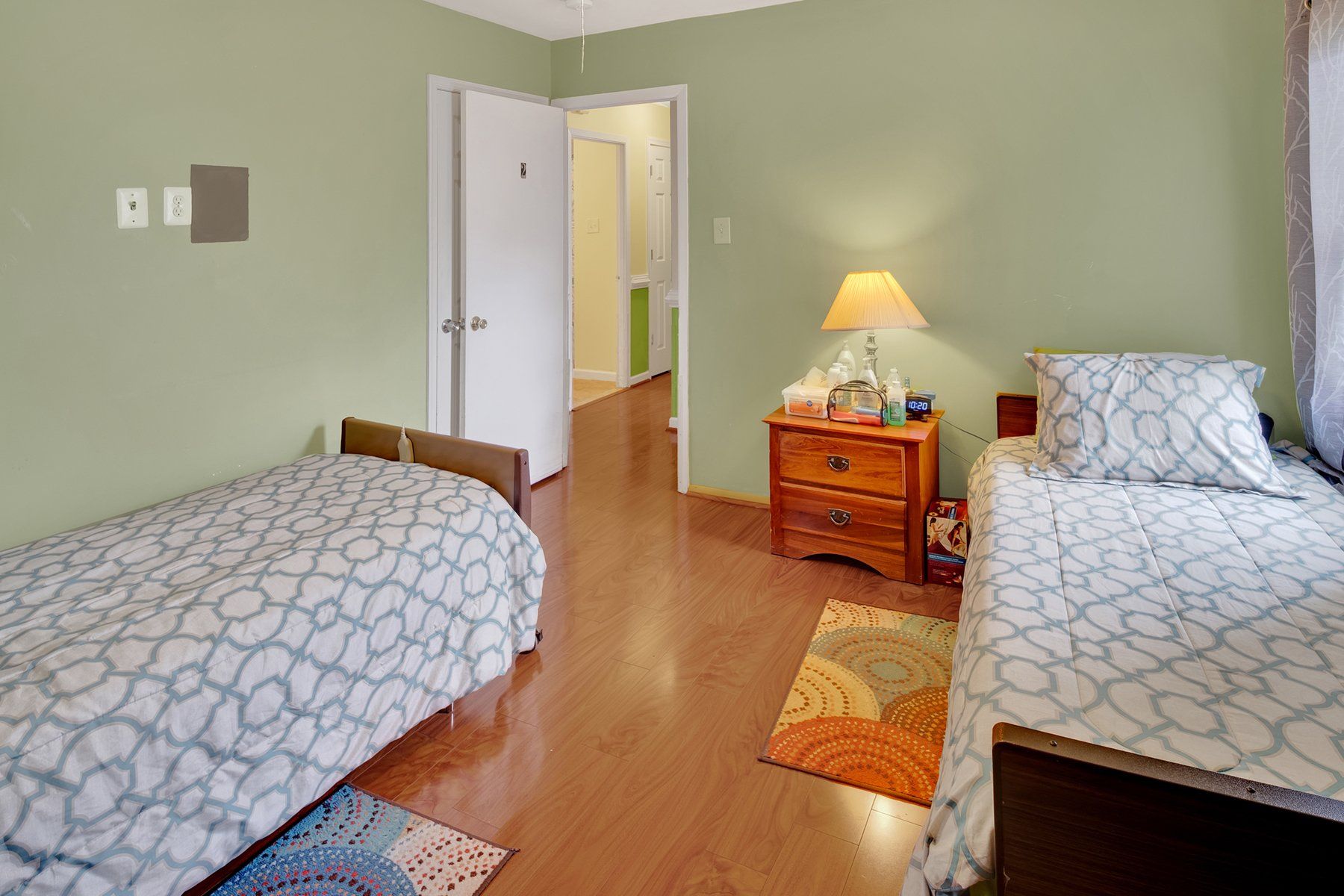 A bedroom with two beds , a nightstand , and a lamp.