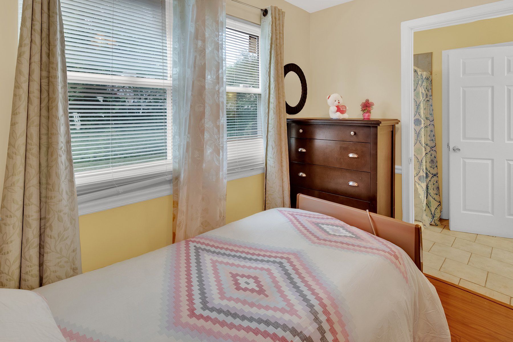 A bedroom with a bed , dresser , and window.