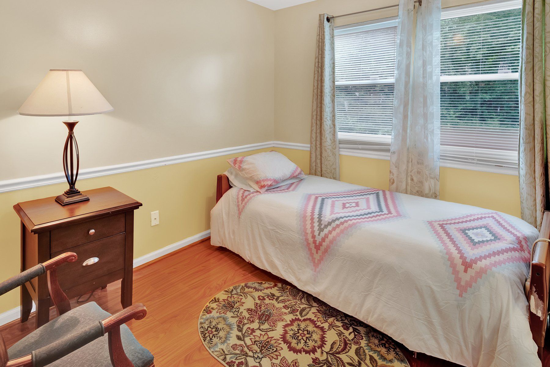 A bedroom with a single bed and a lamp