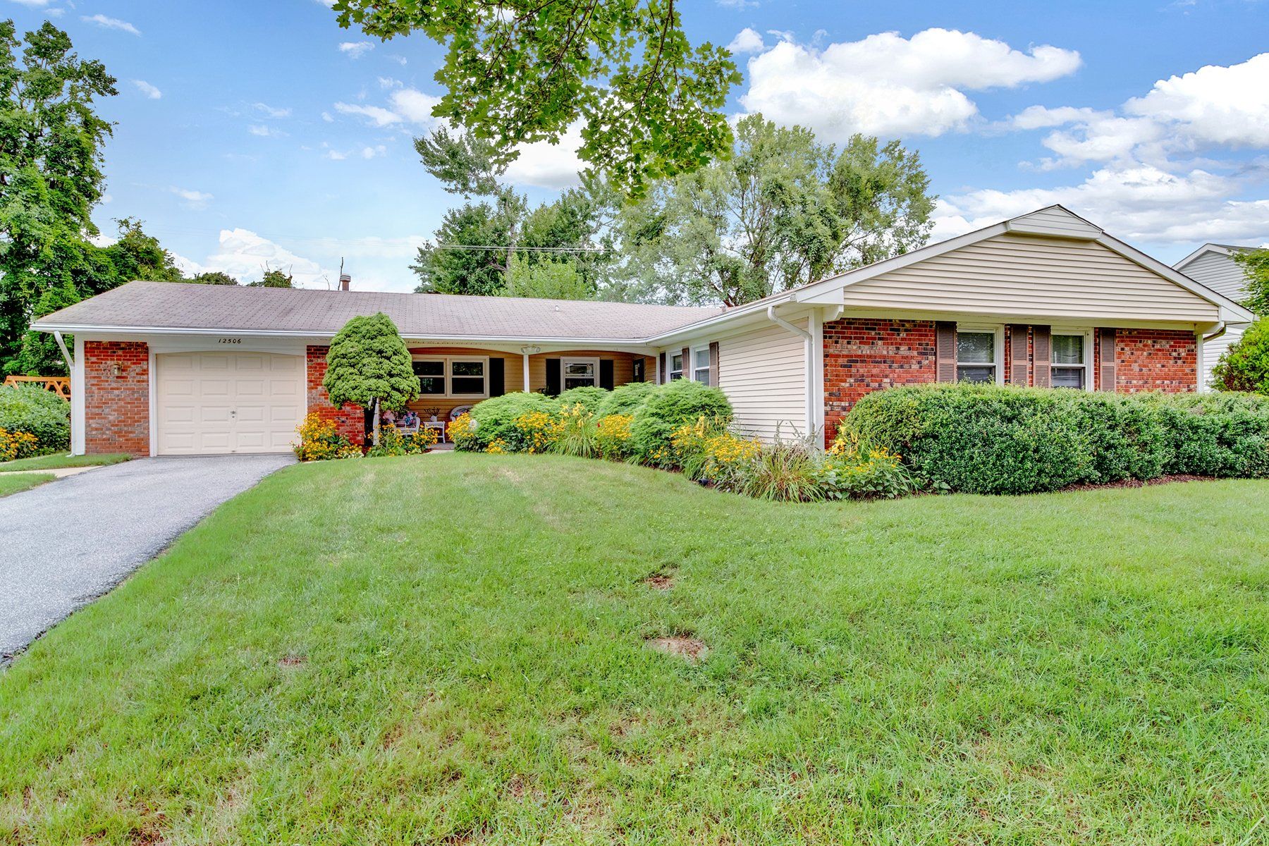 A brick house with a white garage door is for sale