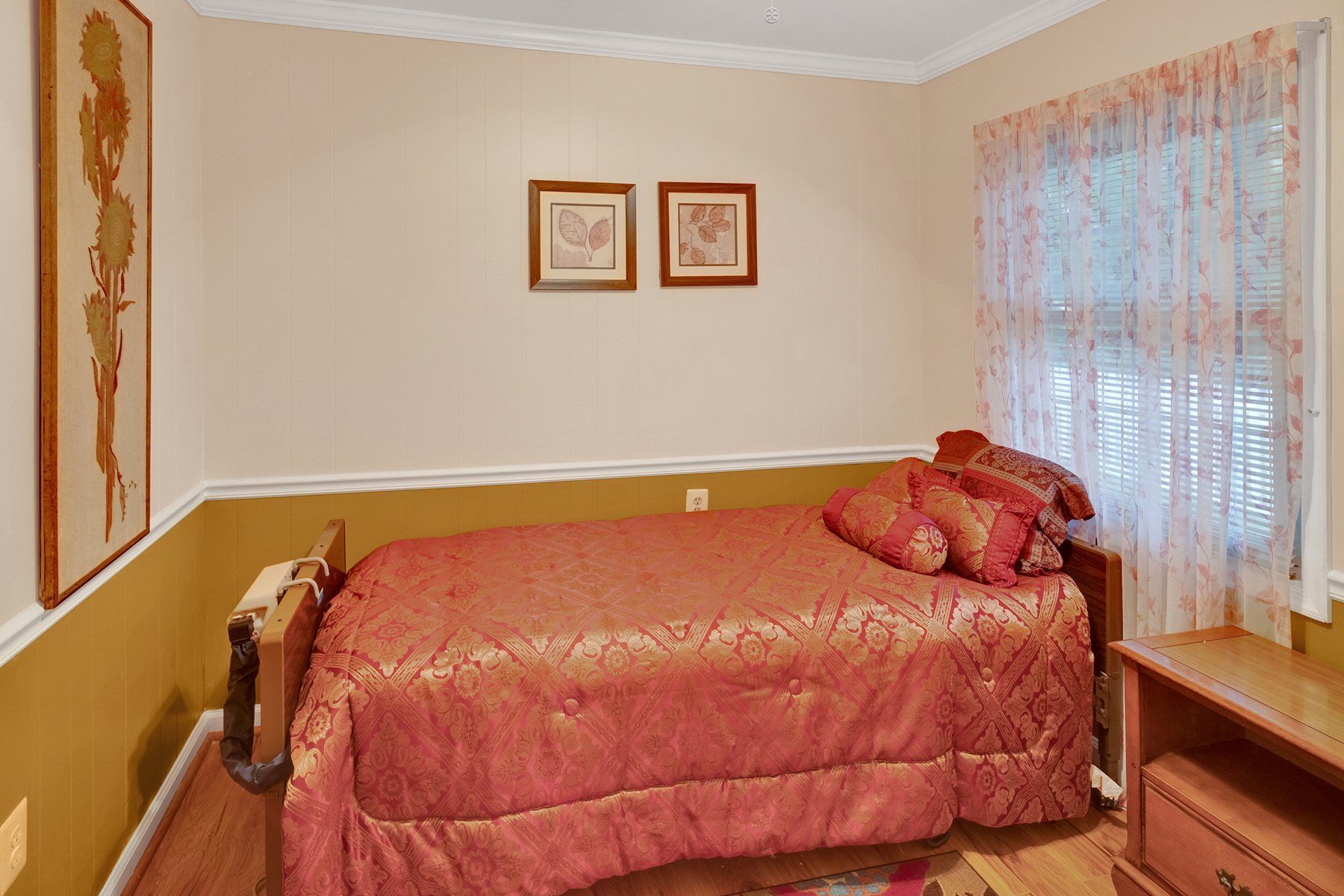 A bedroom with a bed , nightstand , and two pictures on the wall.