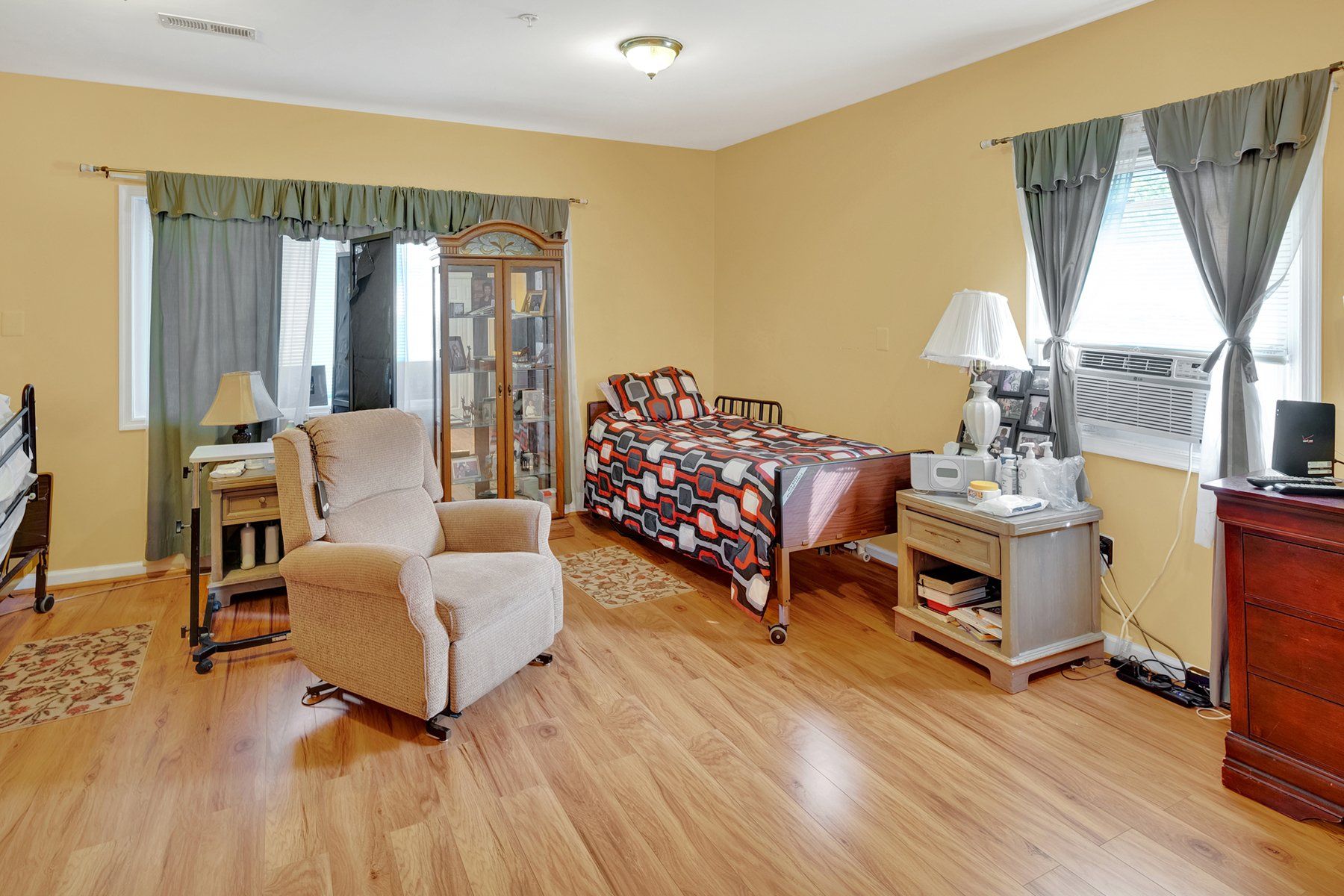 A bedroom with two beds , a chair , and a dresser.