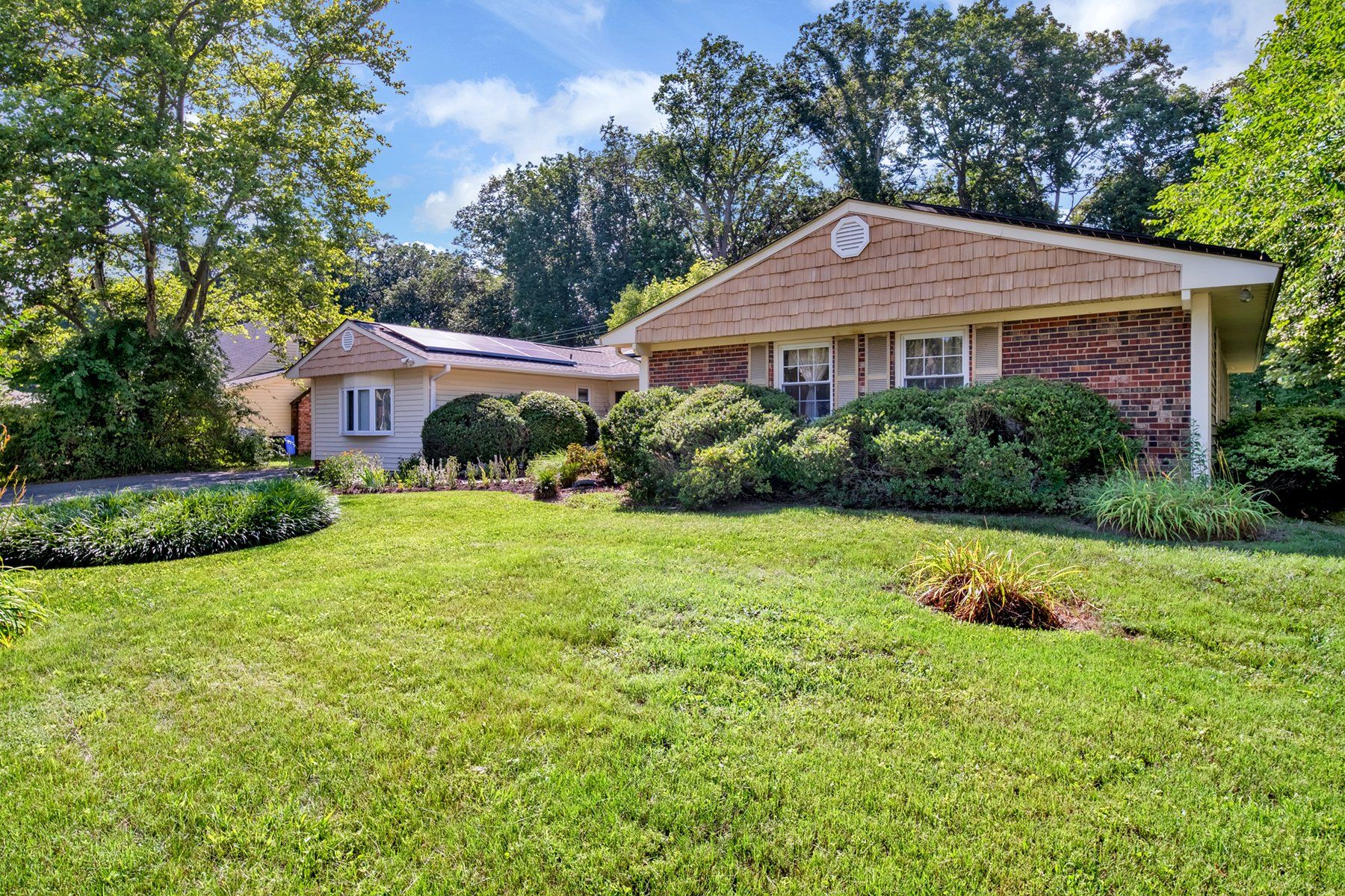 A brick house with a large lush green lawn in front of it.