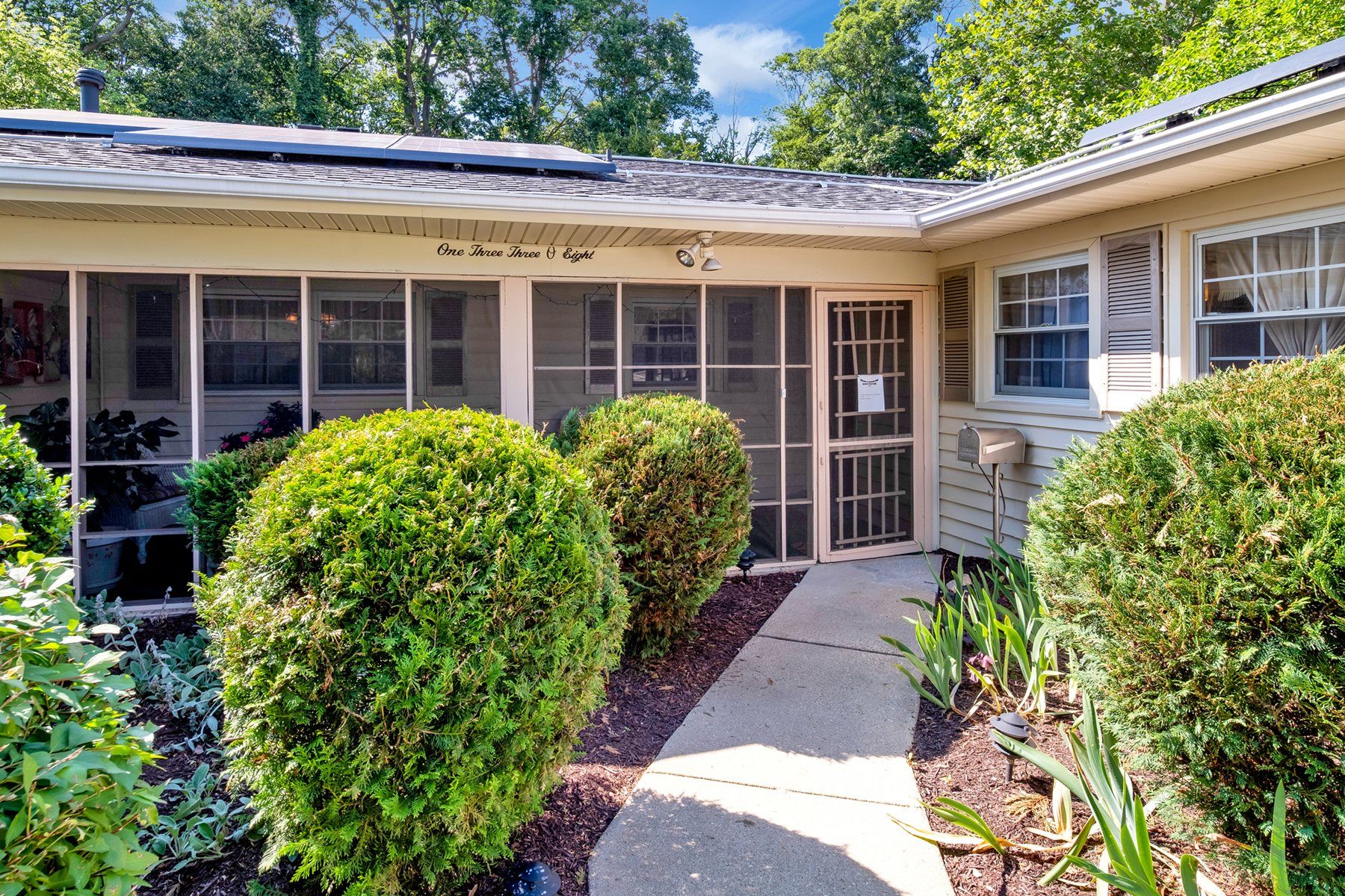 A house with a screened in porch and a walkway leading to it.