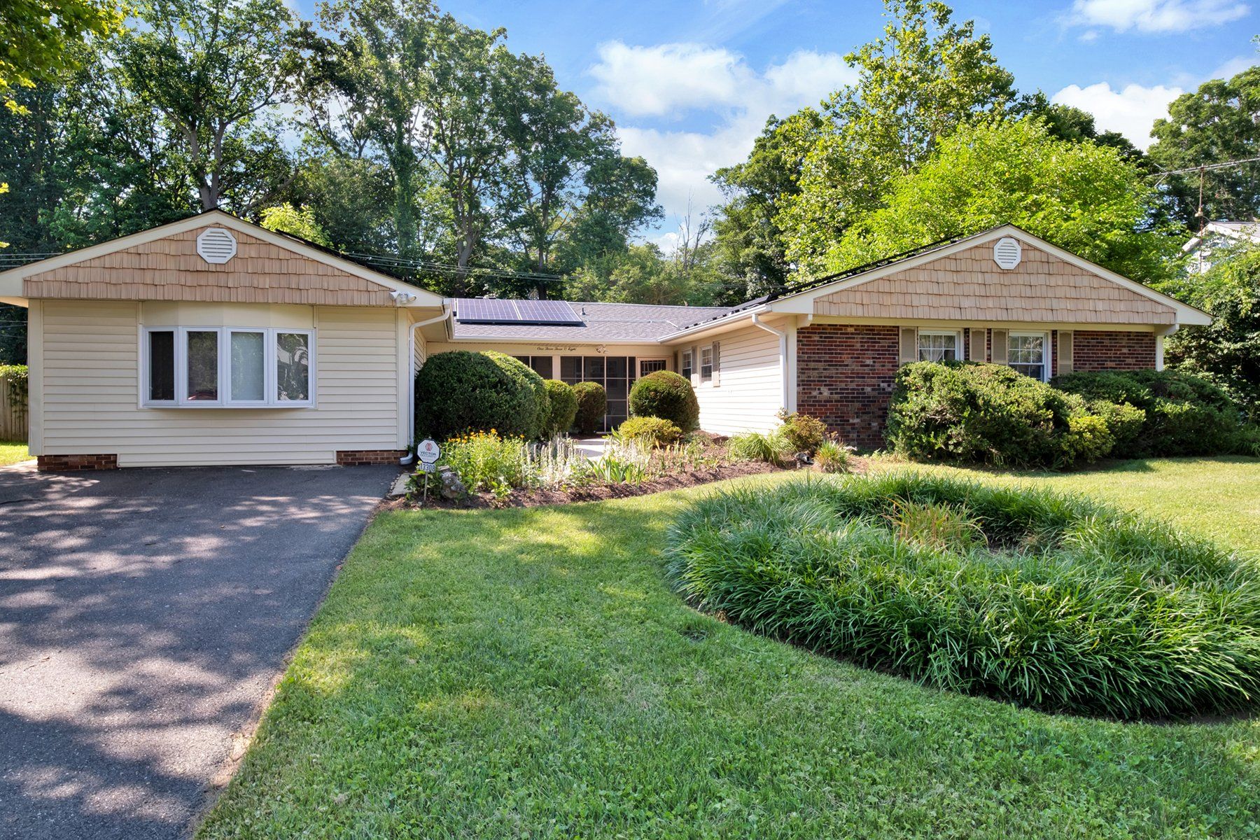 A white house with a brick roof and a driveway