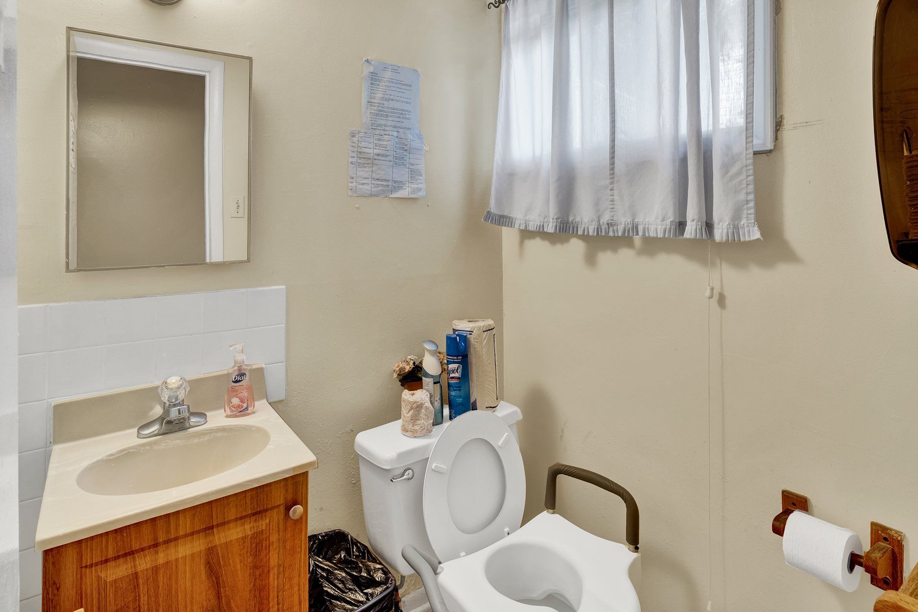 A bathroom with a toilet , sink and mirror.
