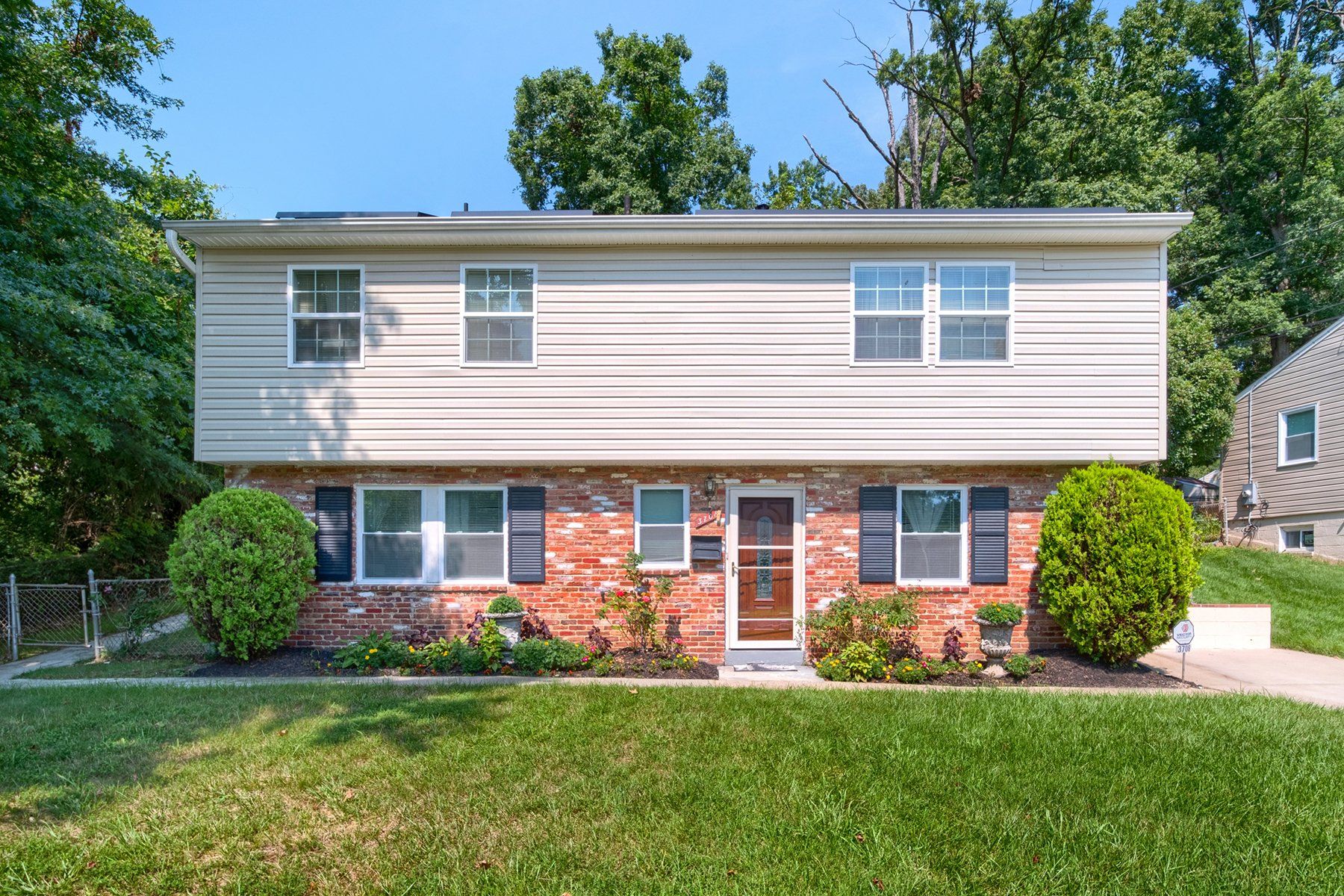 A brick house with a white siding and black shutters is for sale.