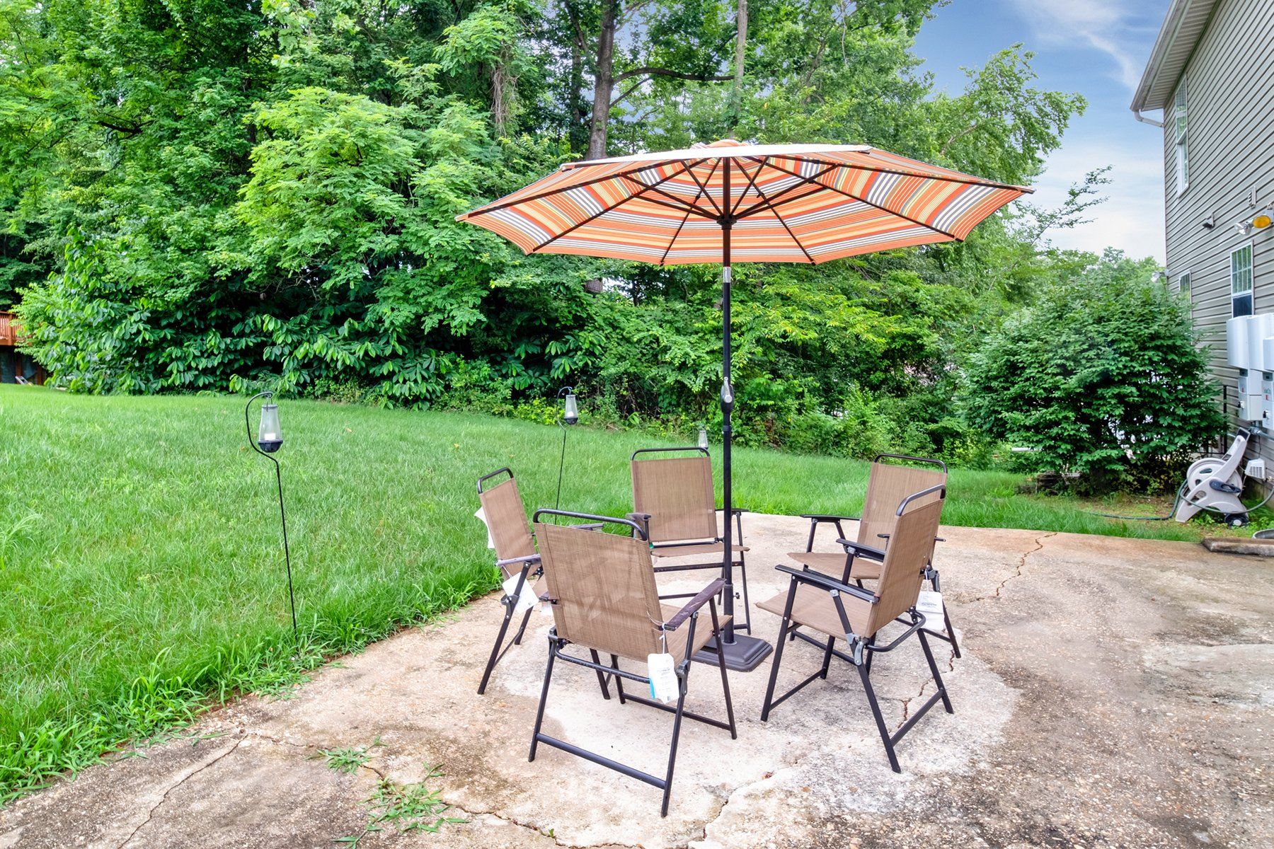 A patio with a table and chairs under an orange umbrella.