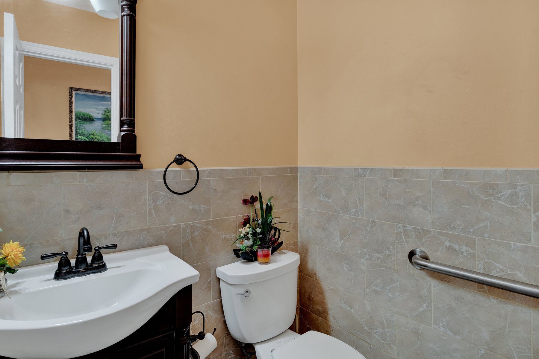 A bathroom with a toilet , sink and mirror.