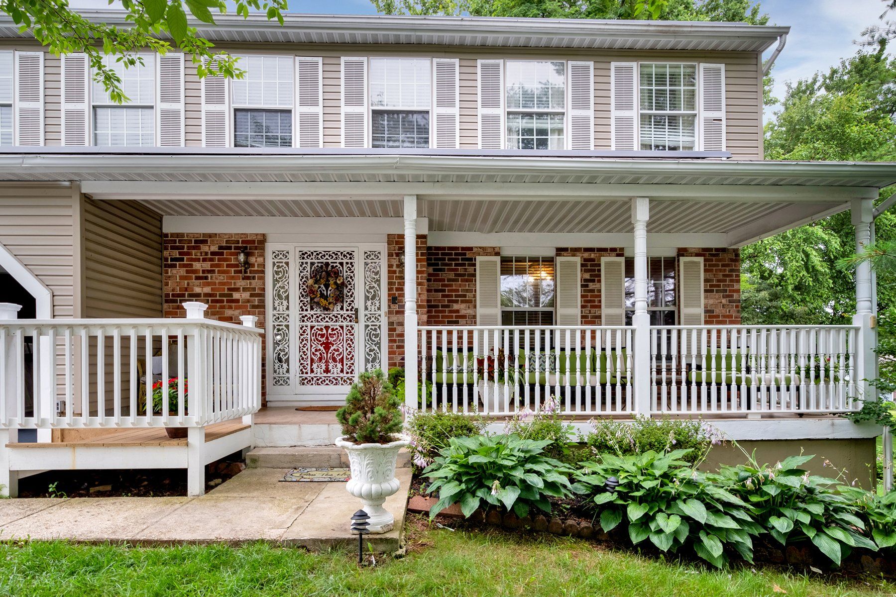 The front of a house with a large porch and a white railing.