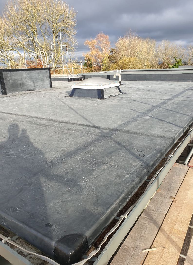 A black roof with a skylight on top of it.