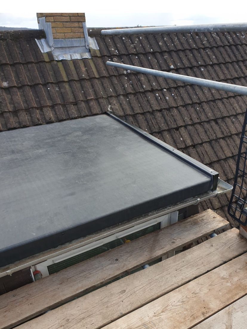 A black roof with a wooden scaffolding on top of it.