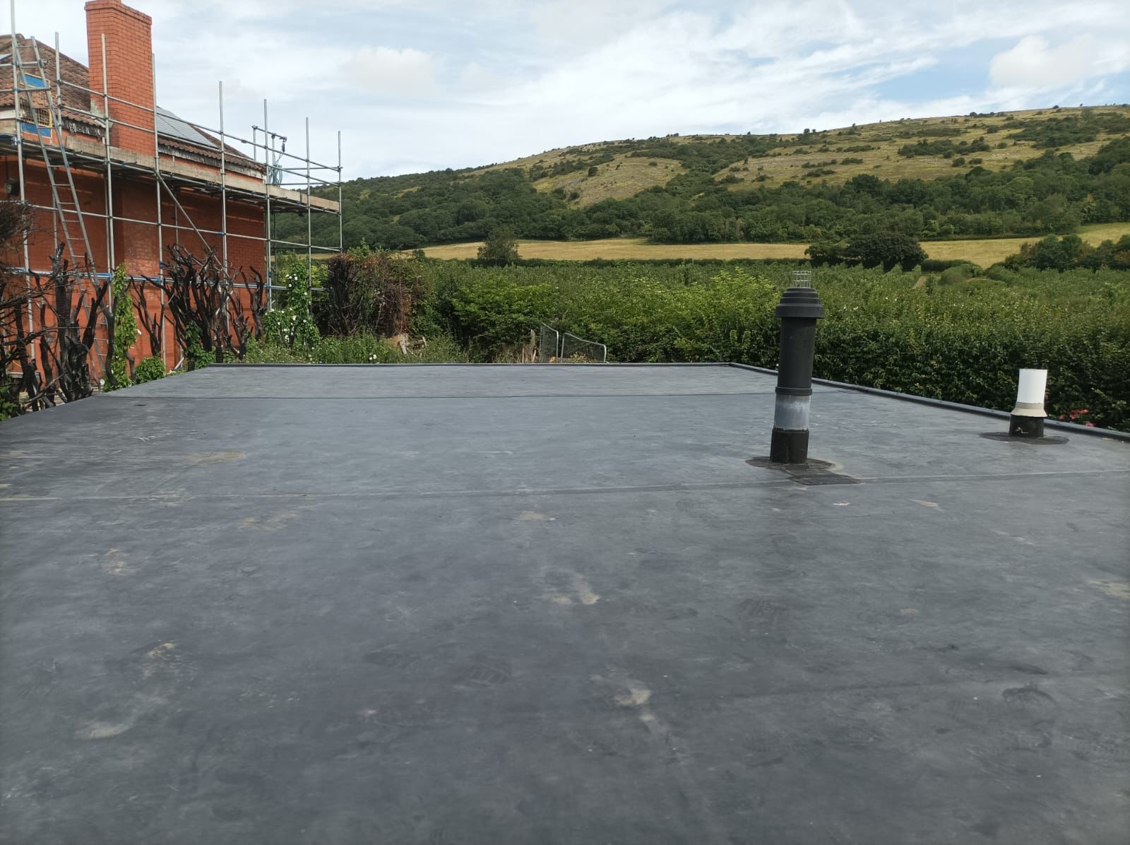 A roof with a chimney on it and a view of a field.