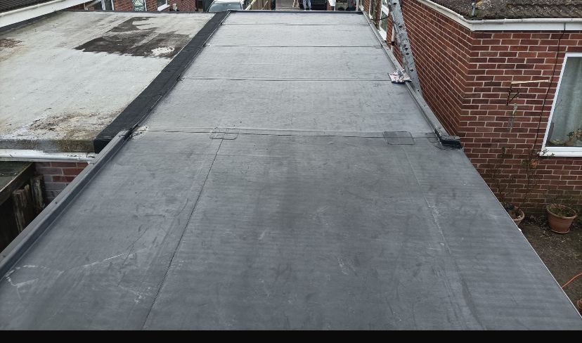 A black roof with a brick building in the background