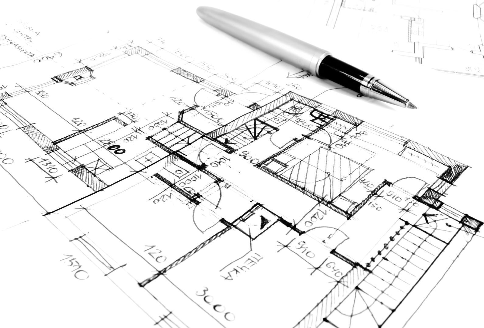 Blueprint with a pen on top, showing a detailed architectural floor plan.