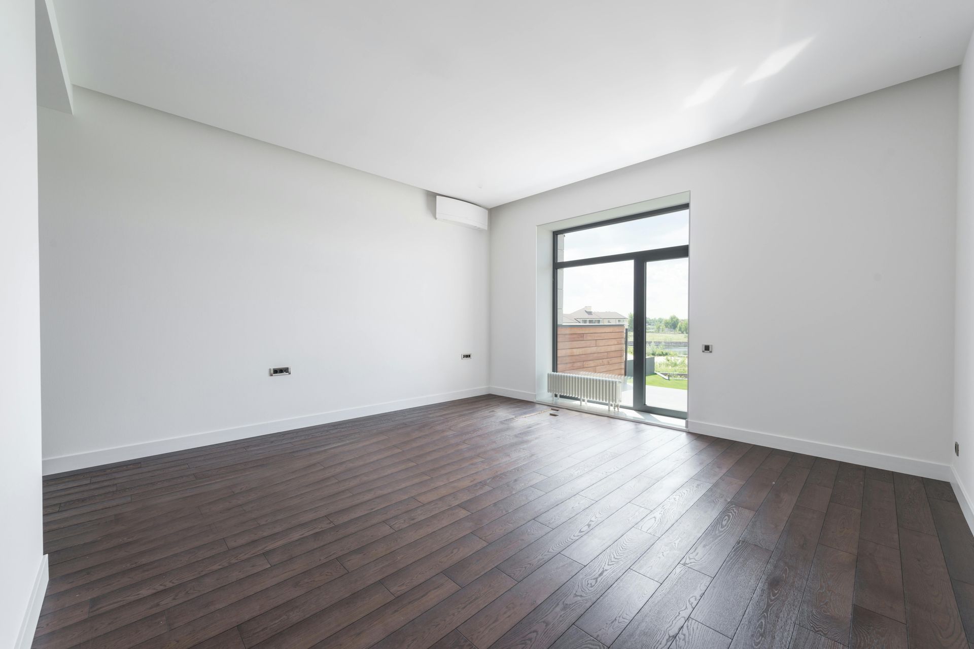 An empty room with hardwood floors and a large window.