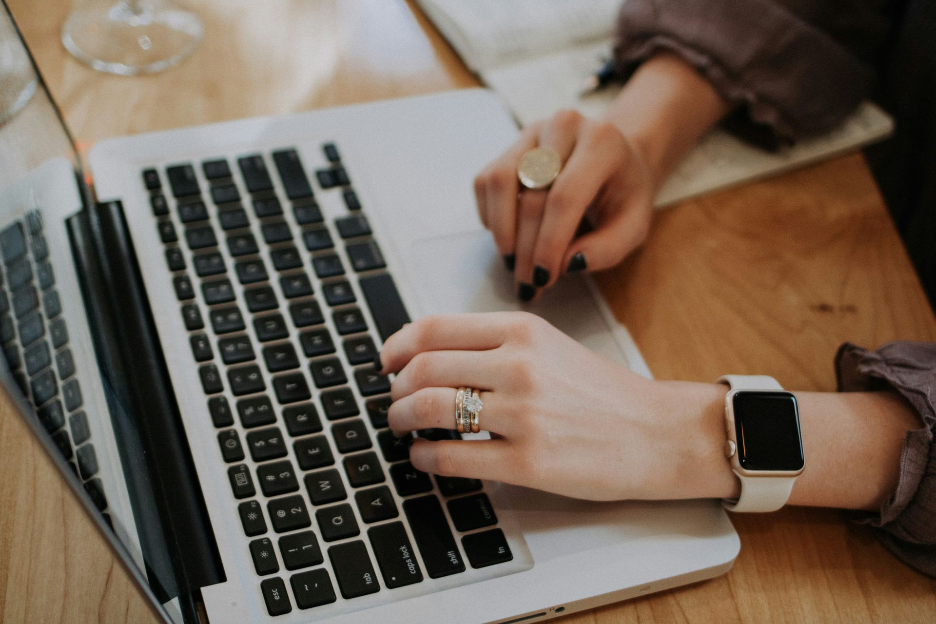 A woman is typing on a laptop computer while wearing a watch.