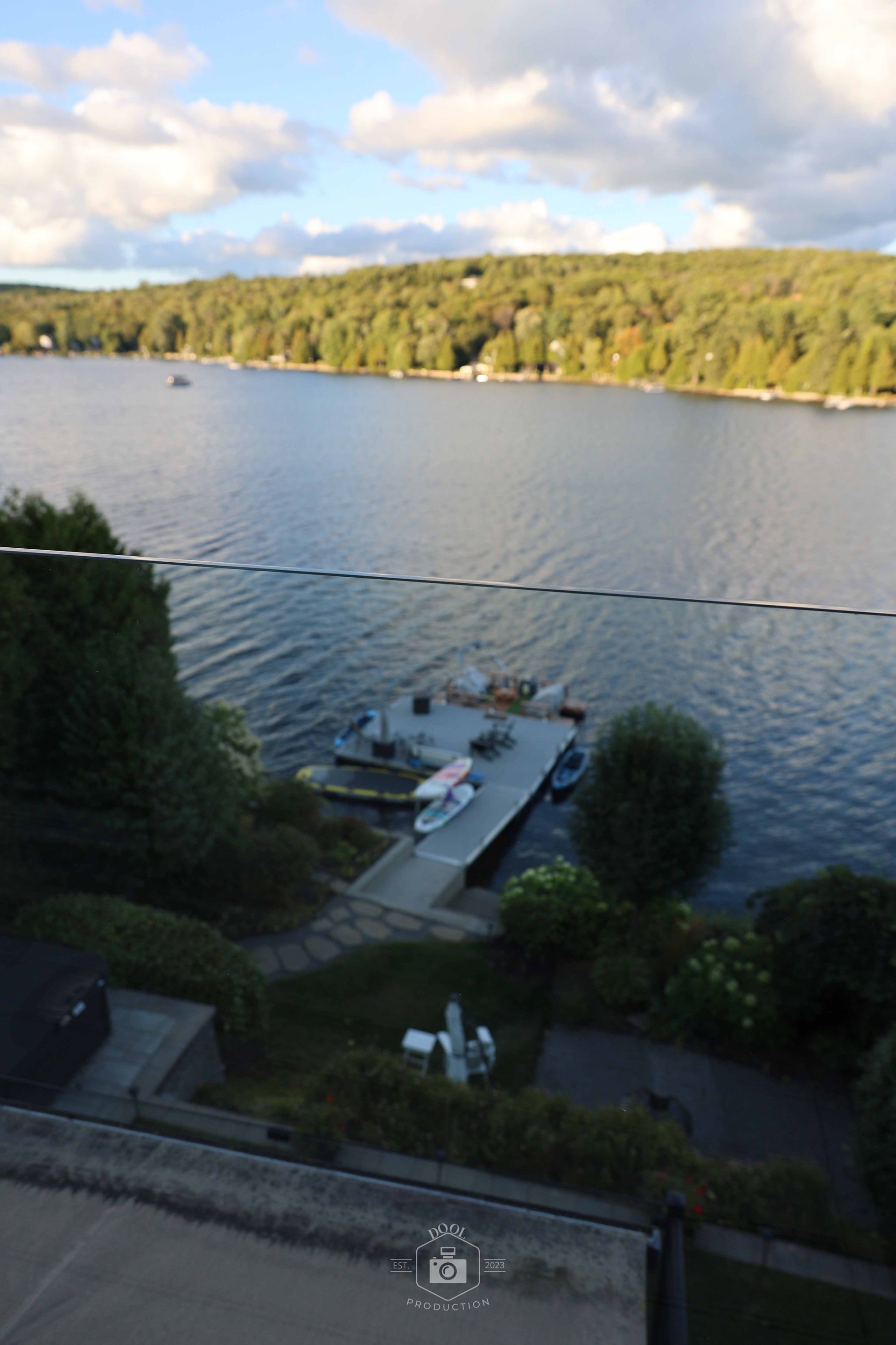 Un quai sur un lac avec des kayaks, entouré d'arbres et d'un ciel nuageux.