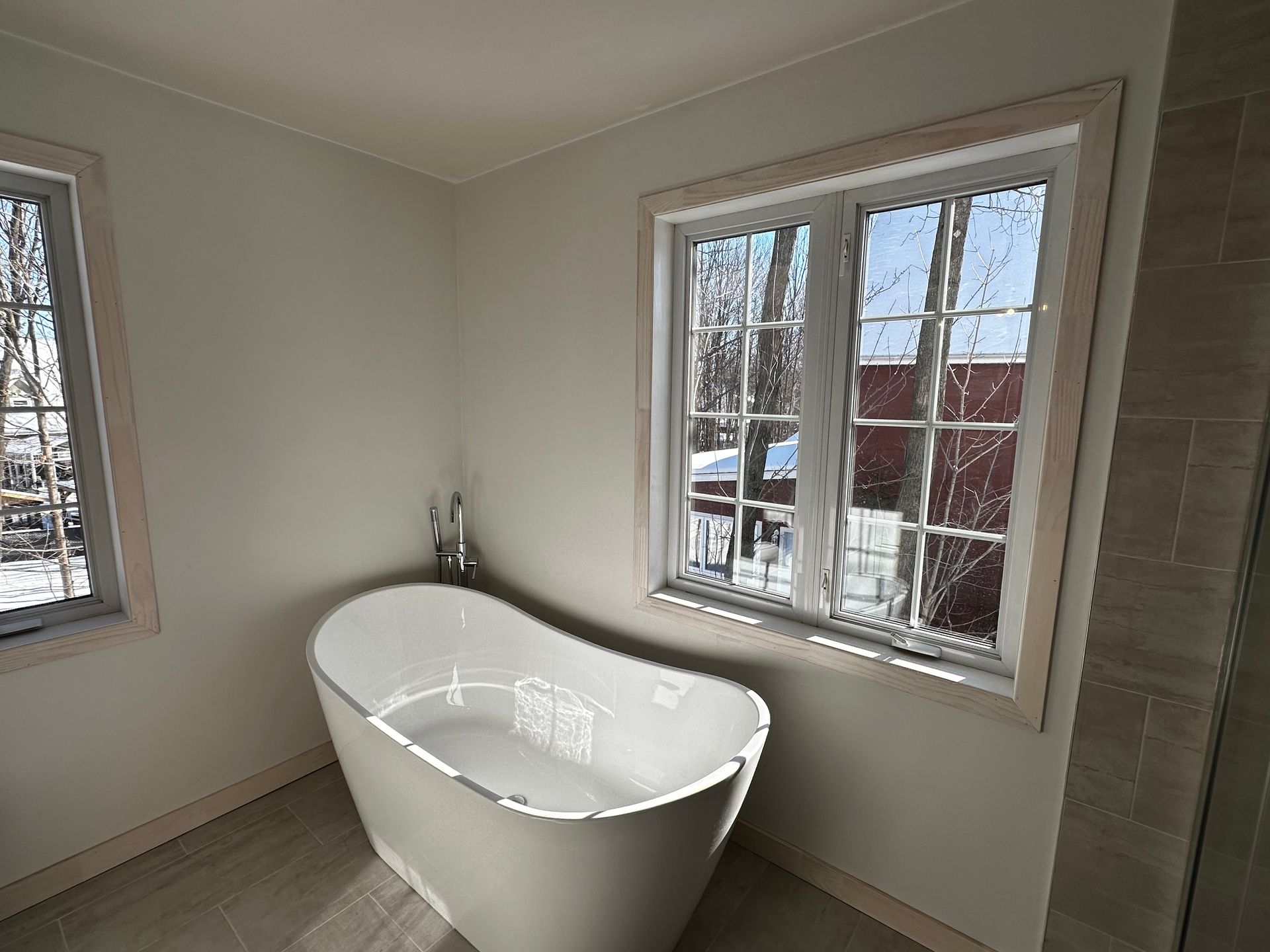 Baignoire îlot près d'une fenêtre dans une salle de bains lumineuse. Paysage d'hiver par la fenêtre.