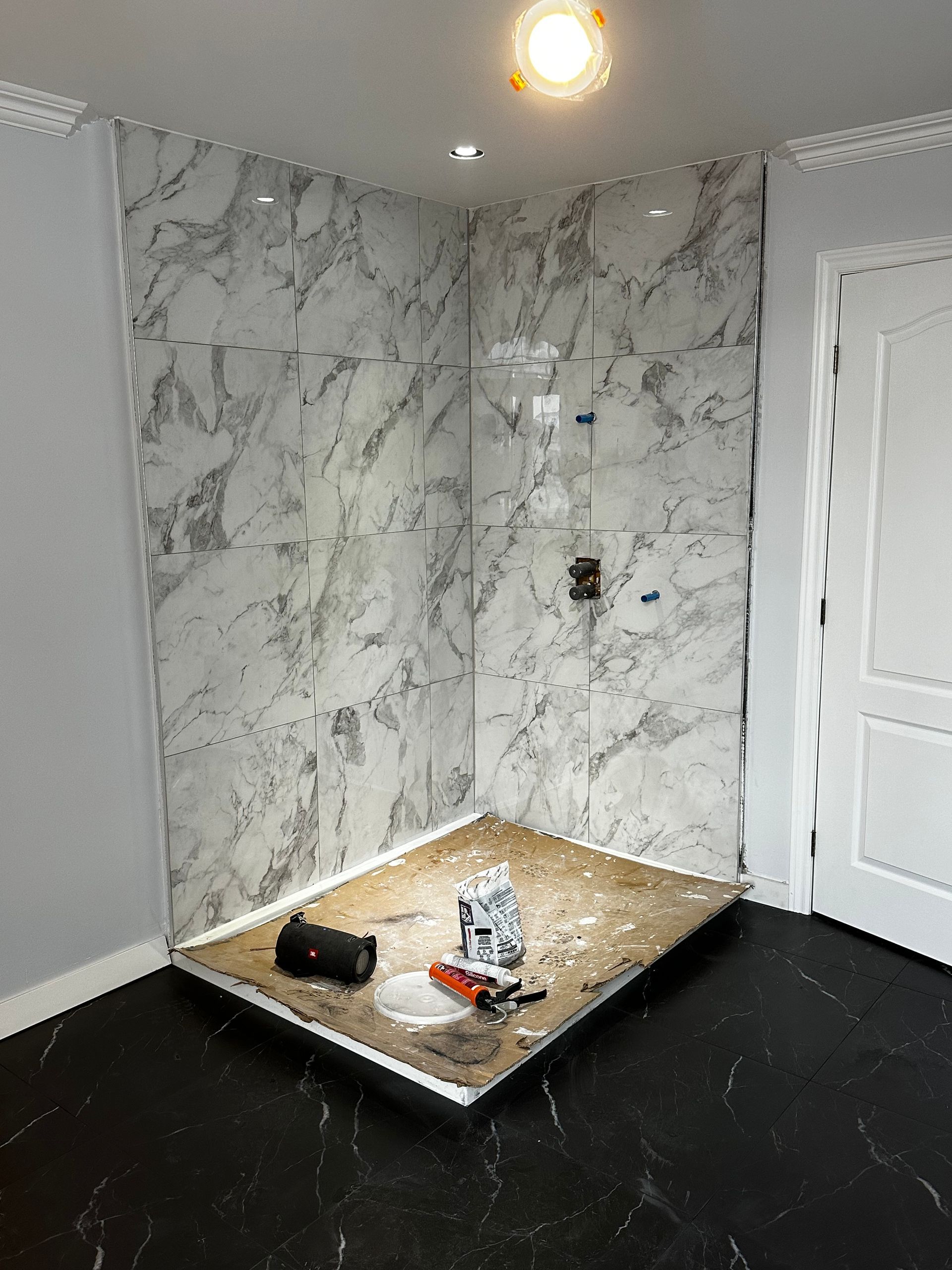 Cabine de douche moderne avec portes en verre, adossée à des murs carrelés et une fenêtre.