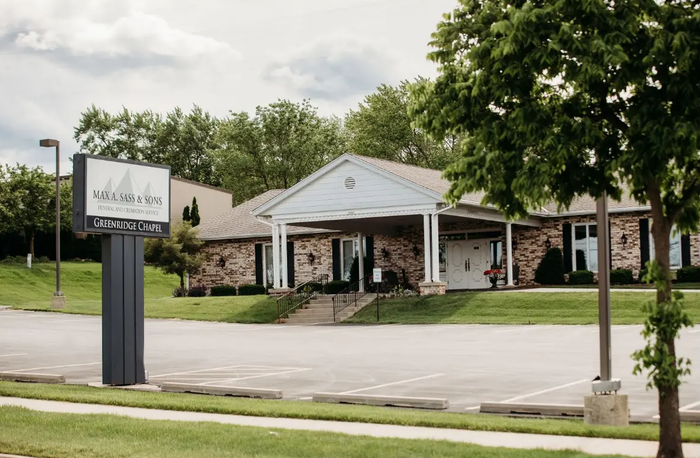 A building with a sign in front of it and a parking lot in front of it.