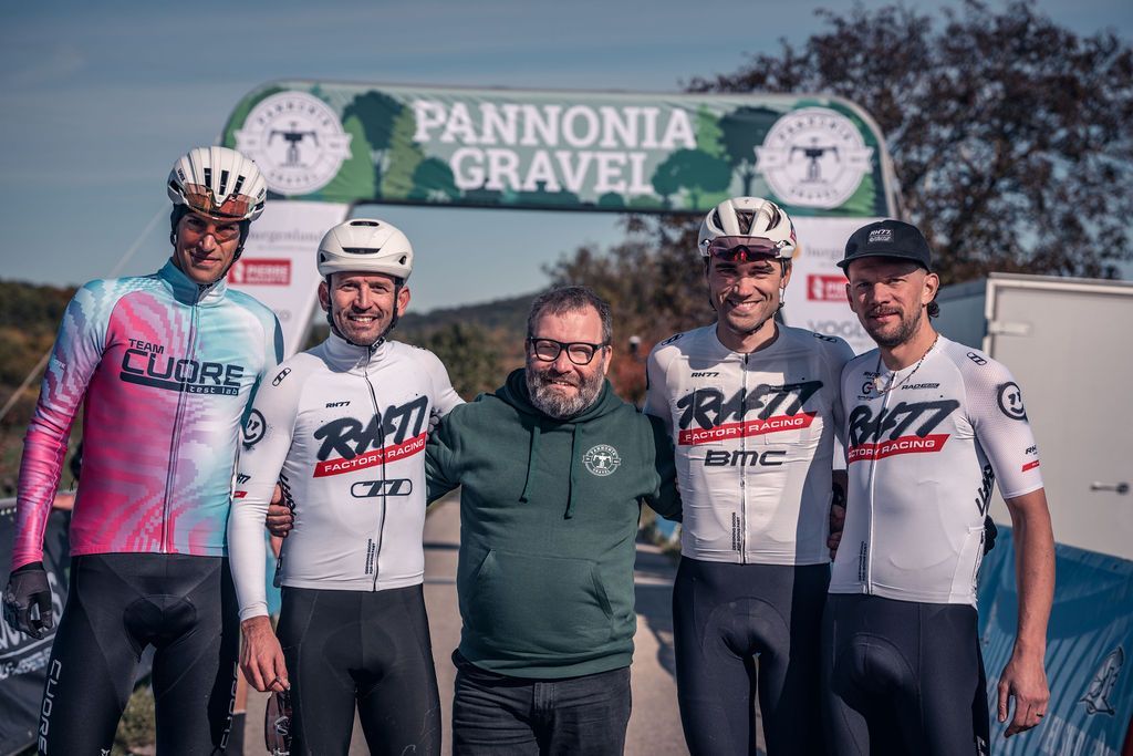 Fünf Radfahrer posieren nach einem Rennen unter einem Banner von Pannonia Gravel.