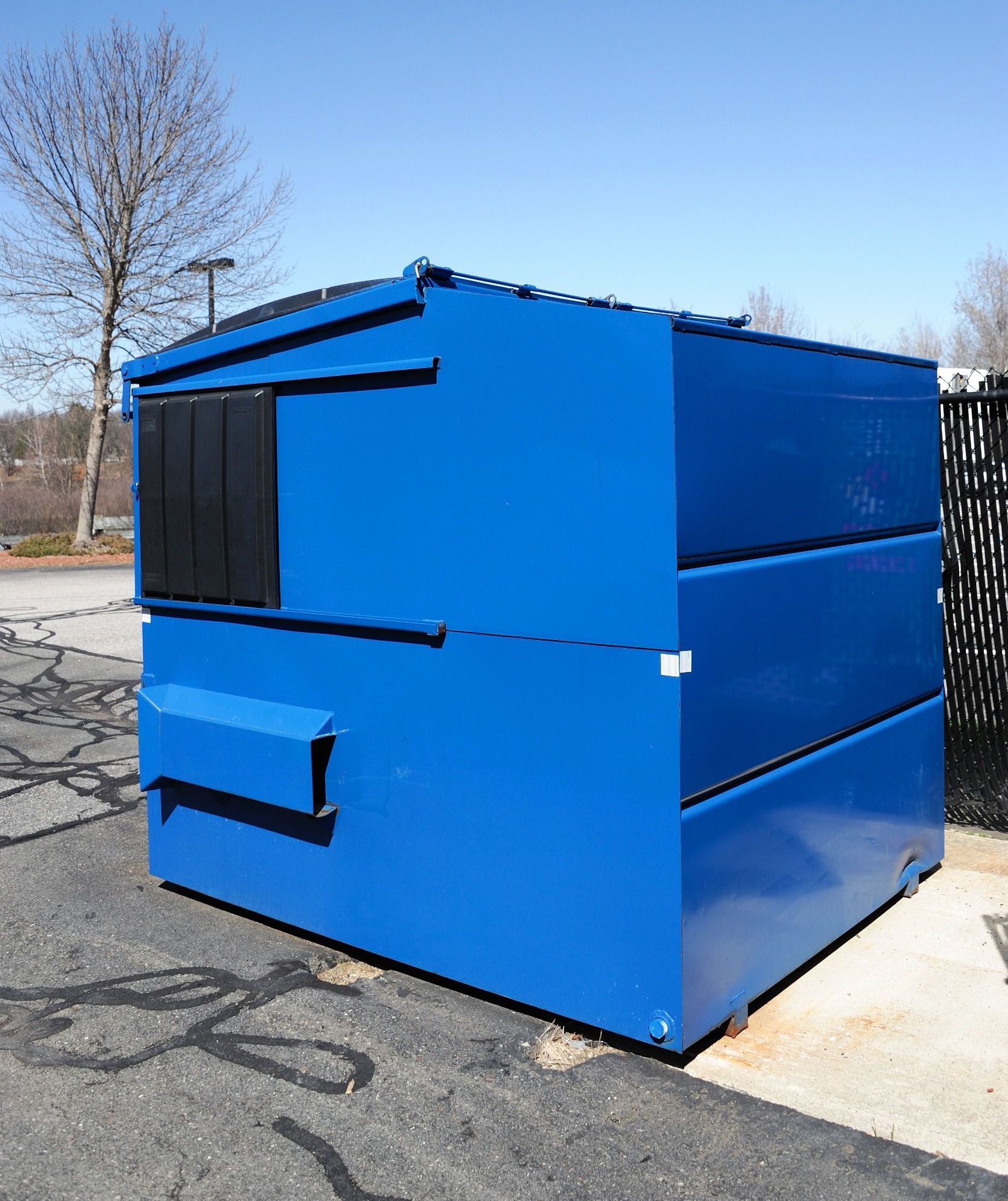 A blue dumpster is sitting on the side of the road