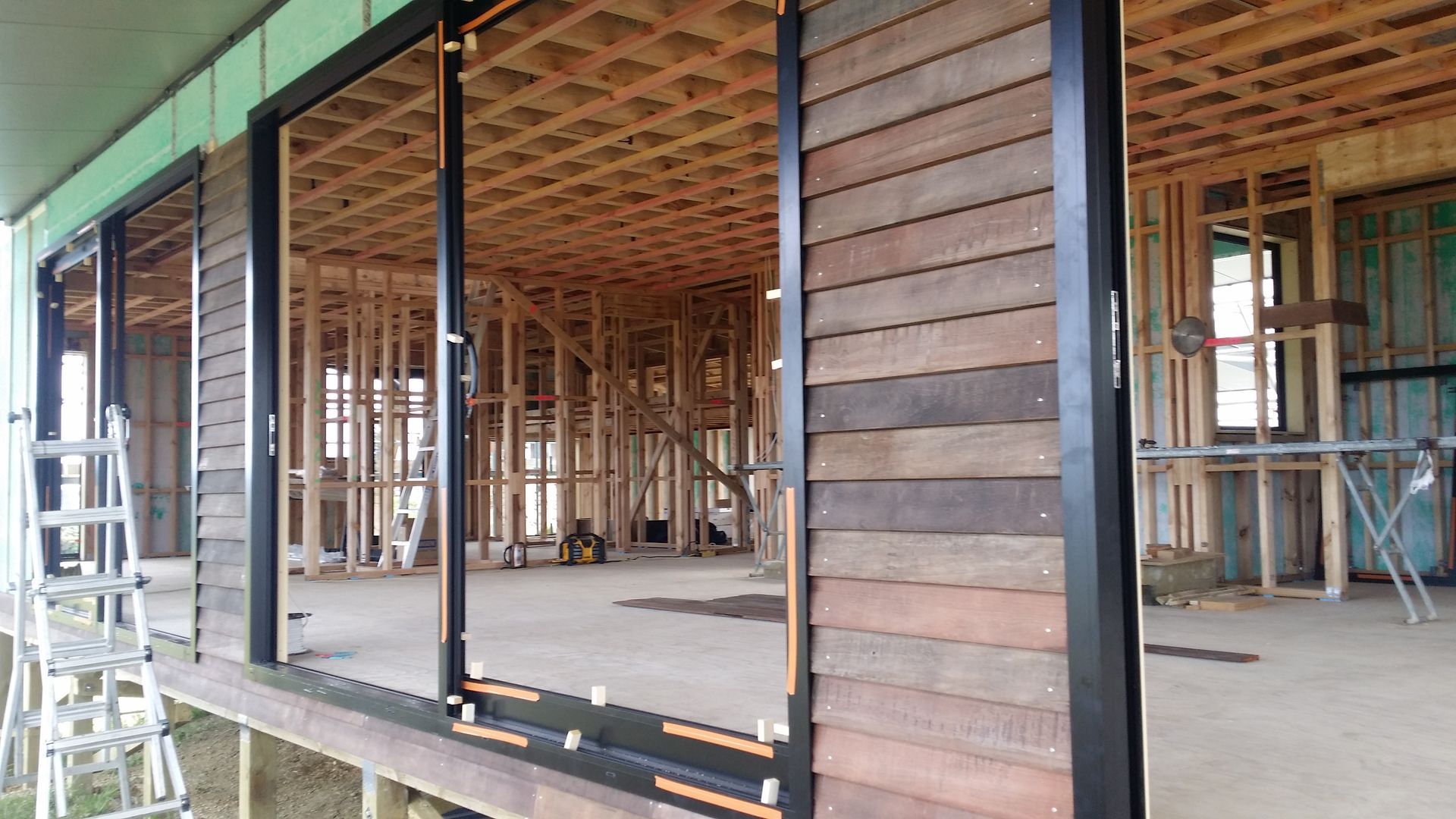 A house is being built with wooden siding and sliding glass doors.